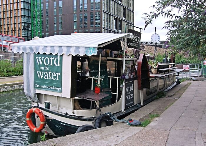Schwimmender Buchladen an einem Kanal festgemacht, der ein gem&uuml;tliches und magisches Bibliothekserlebnis auf dem Wasser bietet.