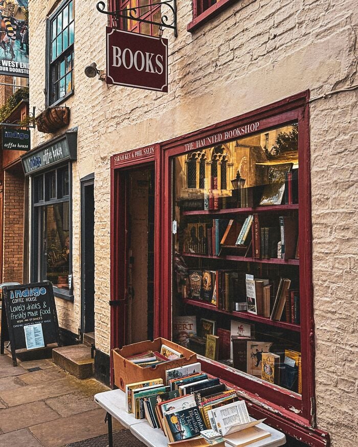 Gem&uuml;tliches und pr&auml;chtiges Buchgesch&auml;ft mit drau&szlig;en ausgestellten B&uuml;chern, das eine charmante Fassade und eine warme, einladende Atmosph&auml;re bietet.