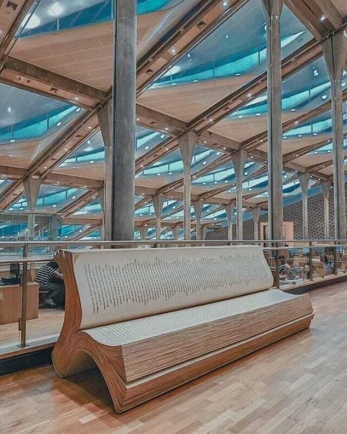 Bench shaped like an open book inside a modern, grandiose library with glass and metal architecture from around the world. Bench shaped like an open book inside a modern, grandiose library with glass and metal architecture from around the world.