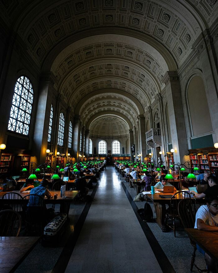 Grandiose Bibliothekseinrichtung mit hohen Gewölbedecken, großen Fenstern und Reihen von Studiertischen mit grünen Lampen und Lesern. Grandiose Bibliothekseinrichtung mit hohen Gewölbedecken, großen Fenstern und Reihen von Studiertischen mit grünen Lampen und Lesern.