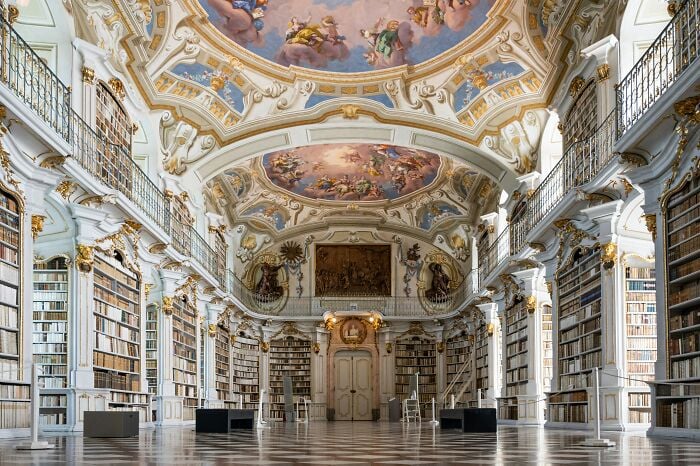 Grandiose Bibliothek mit kunstvollen Decken und hohen B&uuml;cherregalen, gef&uuml;llt mit B&uuml;chern in einer magischen Atmosph&auml;re.